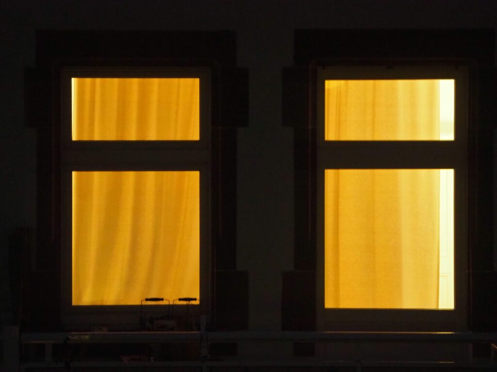 Image of a dark building with two lit-up windows.