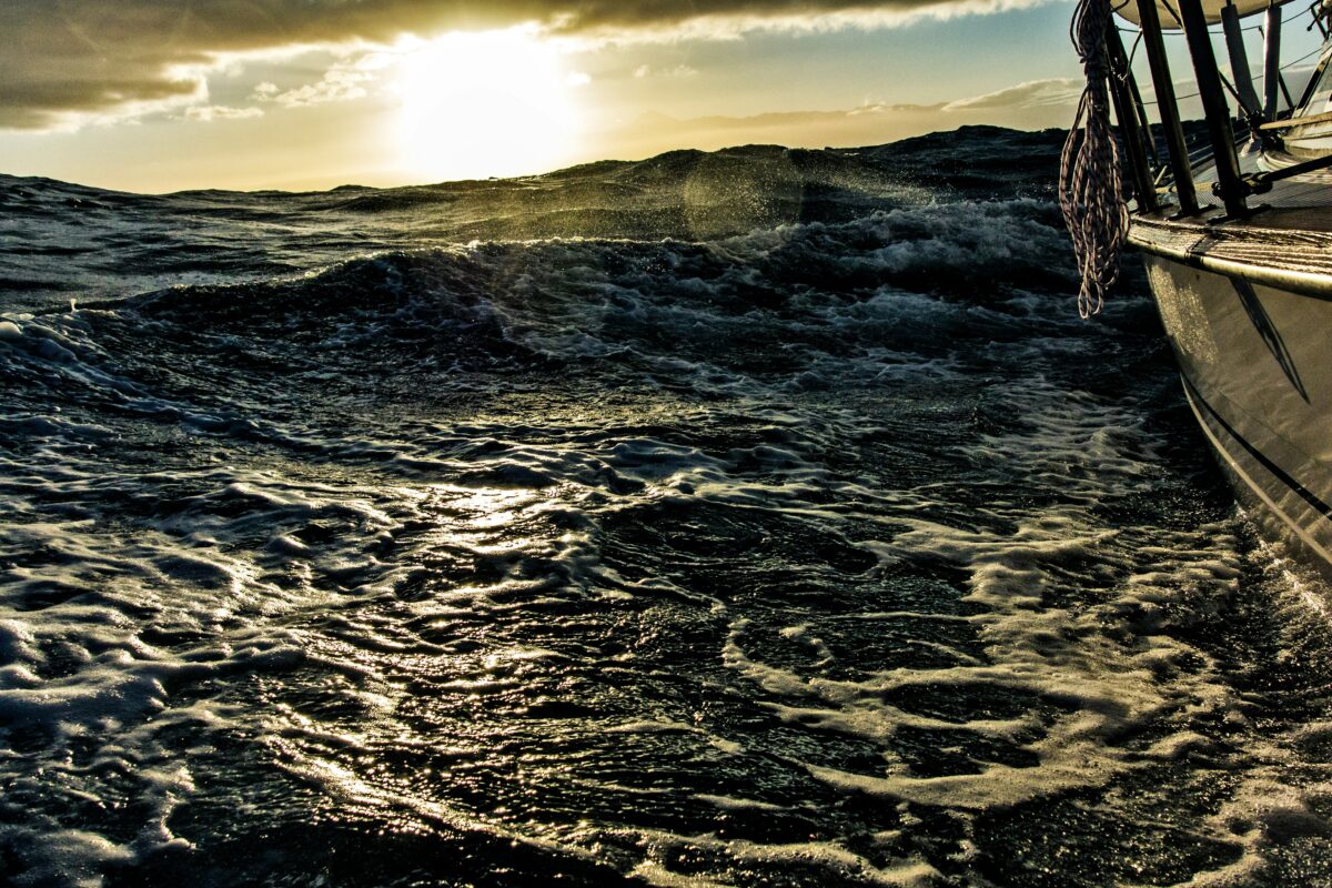 Sun emerges on horizon as a boat navigates heavy seas.